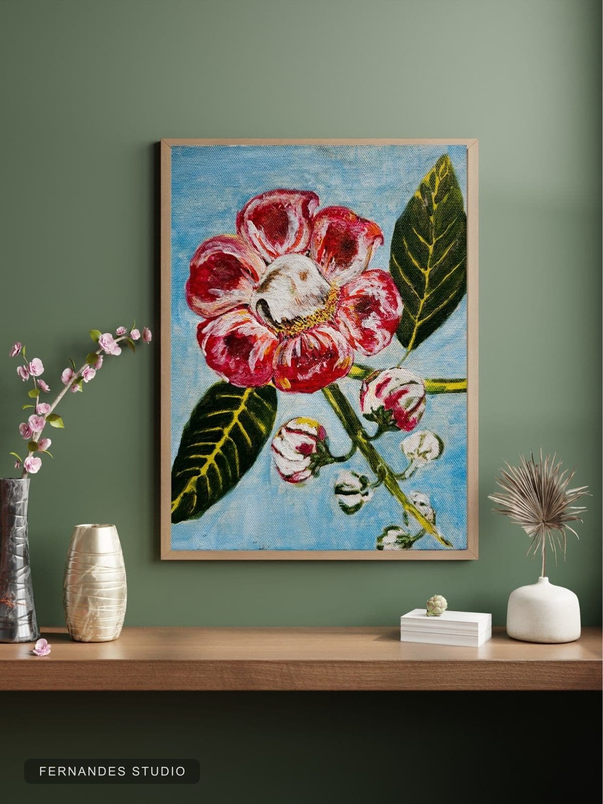 Camellia in Bloom — a red camellia flower with buds and leaves against a blue background, framed on a gallery wall